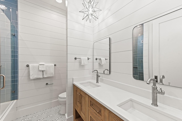 full bathroom with double vanity, a shower with shower door, toilet, and a sink