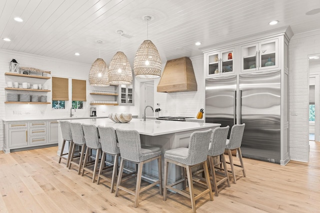 kitchen featuring premium range hood, stainless steel built in refrigerator, open shelves, wooden ceiling, and light countertops