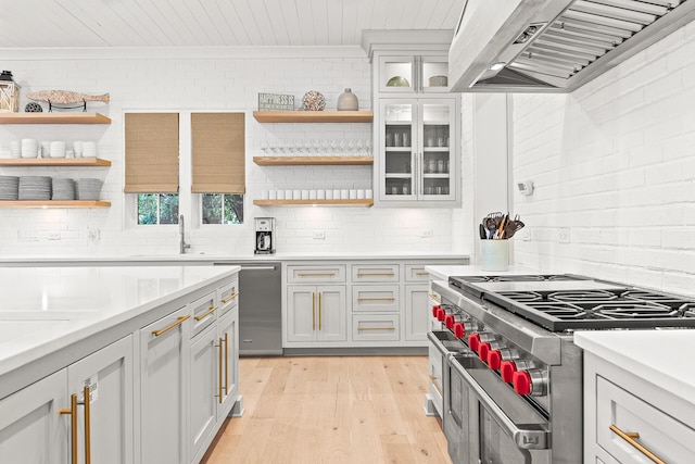 kitchen featuring brick wall, under cabinet range hood, appliances with stainless steel finishes, light wood-style floors, and open shelves