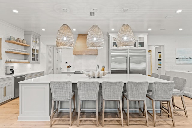 kitchen with a large island, gray cabinetry, custom range hood, appliances with stainless steel finishes, and light countertops