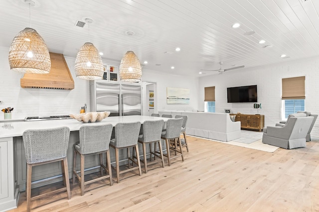 kitchen featuring premium range hood, light wood-style floors, a breakfast bar area, wooden ceiling, and light countertops