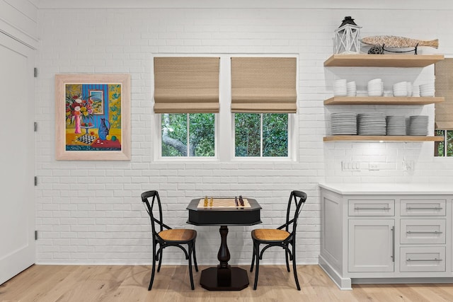 dining area featuring light wood finished floors and brick wall