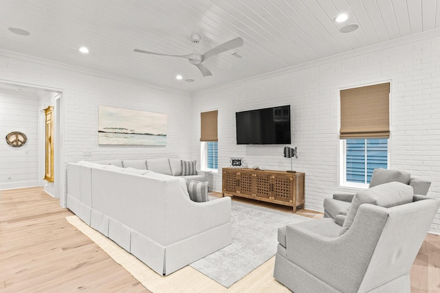 living area with ornamental molding, brick wall, and wood finished floors