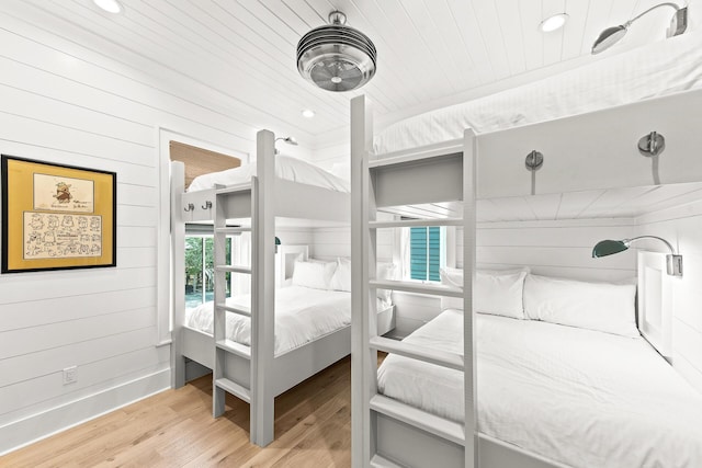 bedroom featuring wooden walls, wooden ceiling, and light wood-style floors