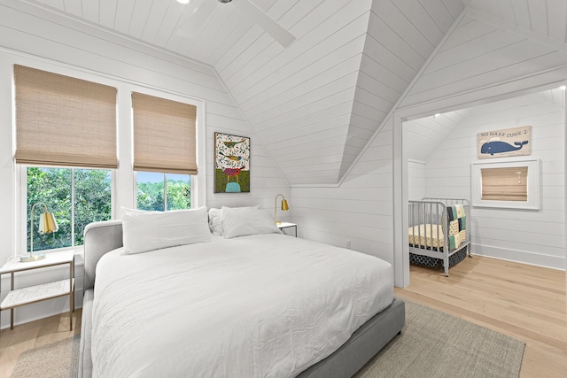 bedroom featuring vaulted ceiling, wood walls, and wood finished floors