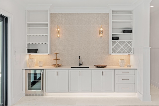 bar with ornamental molding, built in features, beverage cooler, and a sink