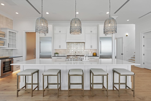 kitchen with a sink, beverage cooler, a spacious island, and stainless steel built in fridge