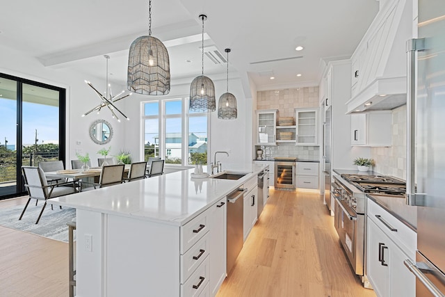 kitchen featuring light wood-style flooring, a sink, backsplash, wine cooler, and high end appliances