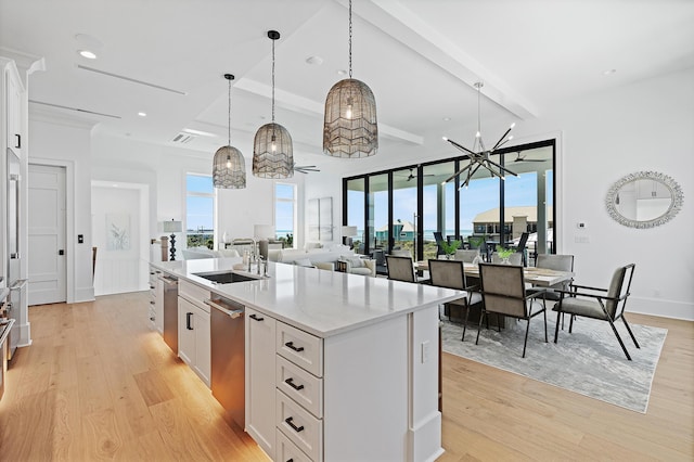 kitchen with a sink, light wood-type flooring, an island with sink, and white cabinets