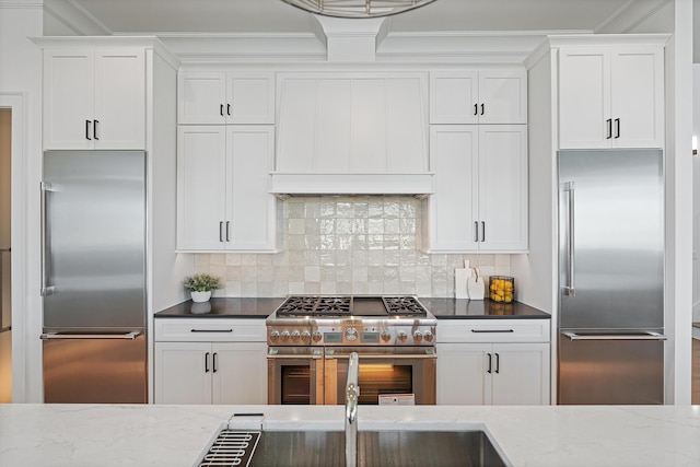 kitchen with tasteful backsplash, white cabinetry, and high end appliances