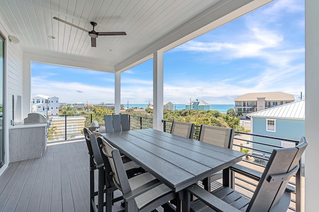 wooden deck with outdoor dining area, a water view, and ceiling fan