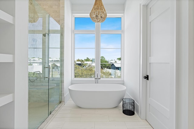 bathroom featuring a notable chandelier, a shower stall, a healthy amount of sunlight, and a freestanding tub