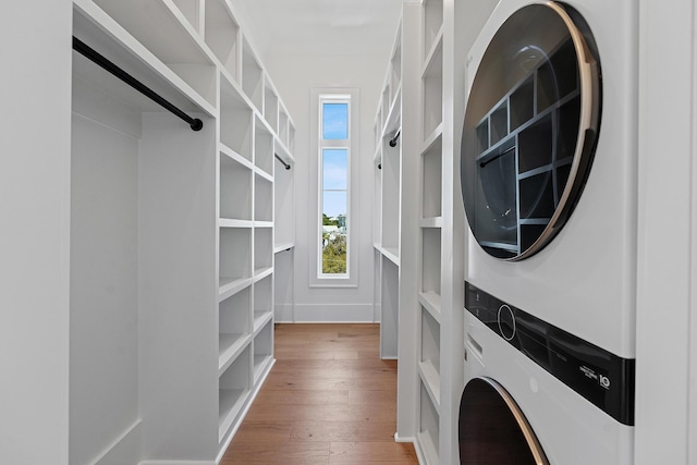 clothes washing area with stacked washer / drying machine and wood finished floors