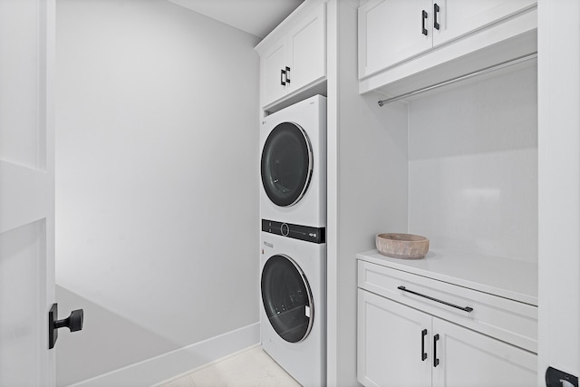 laundry room with stacked washer / drying machine, cabinet space, and baseboards