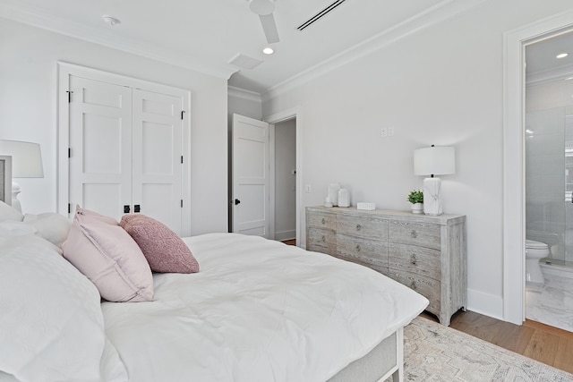 bedroom with connected bathroom, baseboards, ornamental molding, wood finished floors, and a closet