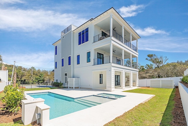 back of property with a patio, a balcony, a fenced backyard, ceiling fan, and a lawn