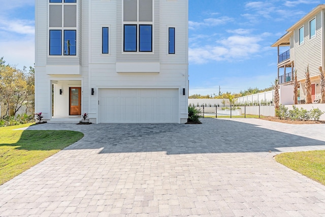 view of front of house with decorative driveway, a garage, a front yard, and fence