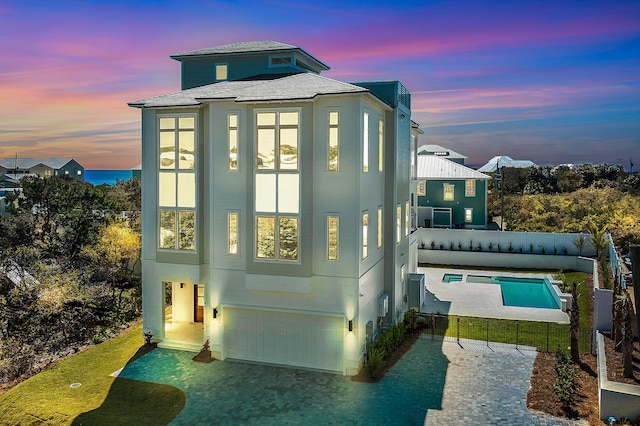 back of property with a fenced in pool, a shingled roof, fence private yard, decorative driveway, and a garage