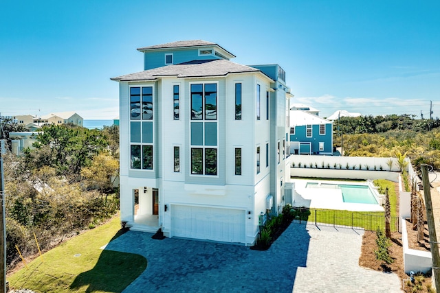 view of front of home featuring decorative driveway, a garage, and fence