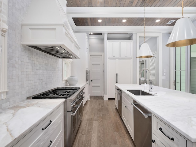 kitchen featuring wood finished floors, beam ceiling, a sink, stainless steel appliances, and tasteful backsplash