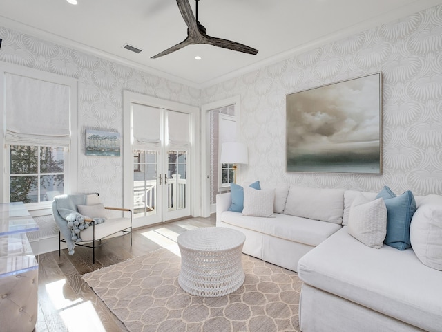 living room featuring wood finished floors, visible vents, wallpapered walls, recessed lighting, and ornamental molding