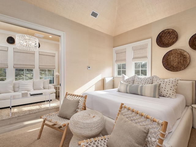 bedroom with visible vents, a notable chandelier, and wood finished floors