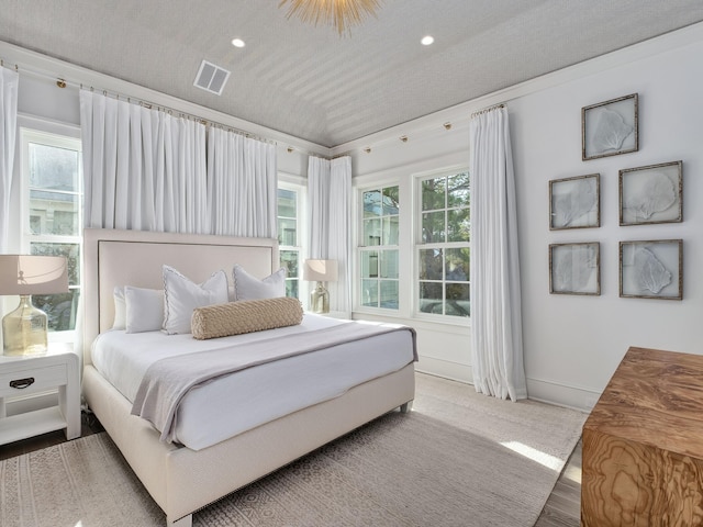 bedroom with lofted ceiling, multiple windows, baseboards, and visible vents