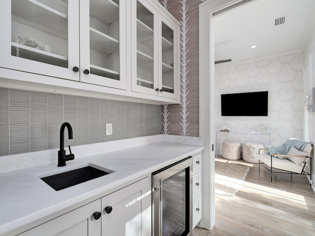 bar with visible vents, light wood-type flooring, a sink, wine cooler, and wallpapered walls