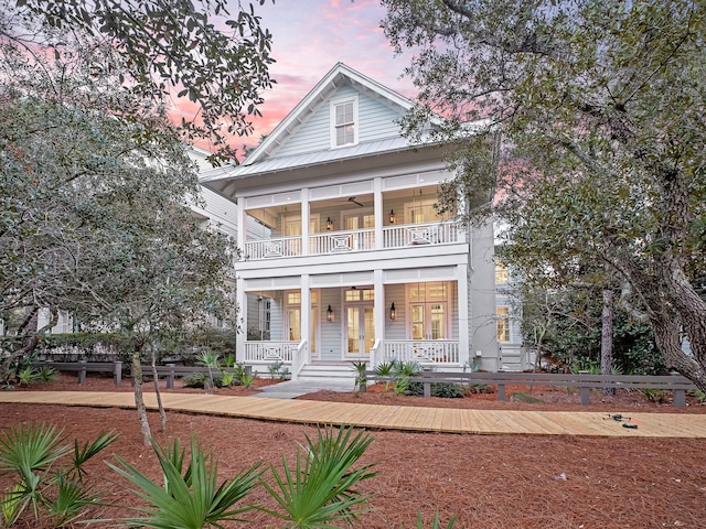 neoclassical / greek revival house featuring french doors, a balcony, covered porch, and metal roof