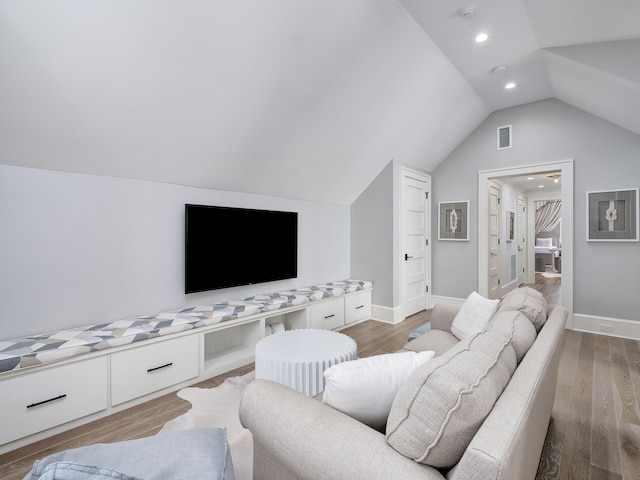 living room with lofted ceiling, wood finished floors, visible vents, and baseboards