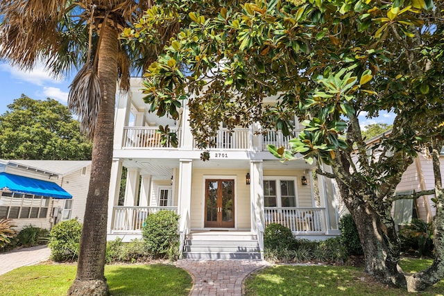 view of front facade featuring a balcony, french doors, and covered porch