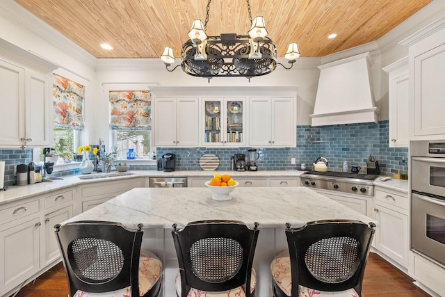 kitchen featuring a breakfast bar area, appliances with stainless steel finishes, wooden ceiling, custom exhaust hood, and white cabinetry