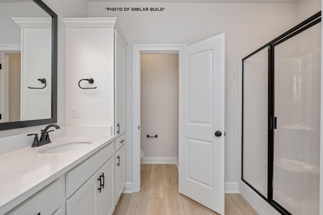 full bathroom featuring vanity, a shower stall, toilet, and wood finished floors