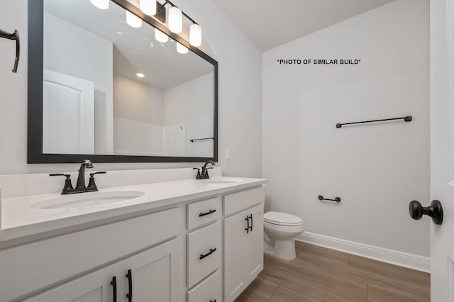 bathroom with a sink, baseboards, toilet, and double vanity