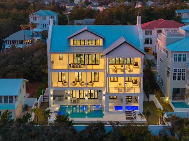 back of property featuring metal roof, a standing seam roof, fence, and a balcony