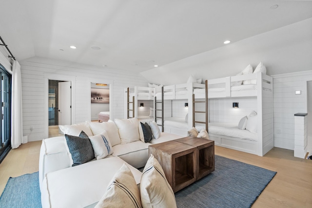 living area featuring wooden walls, lofted ceiling, and light wood-type flooring