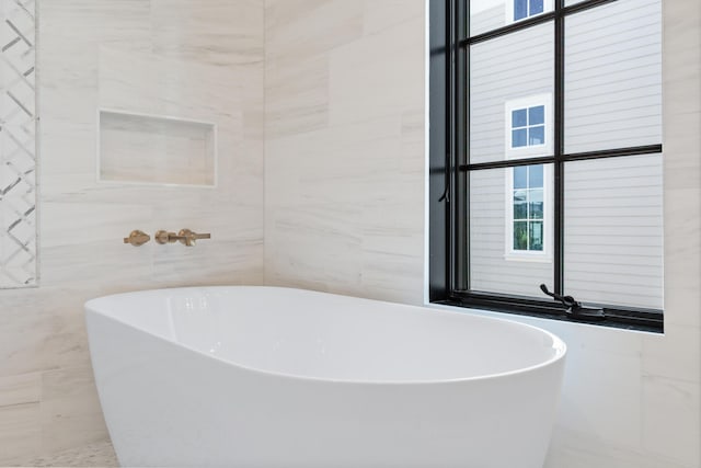 bathroom featuring tile walls and a freestanding tub
