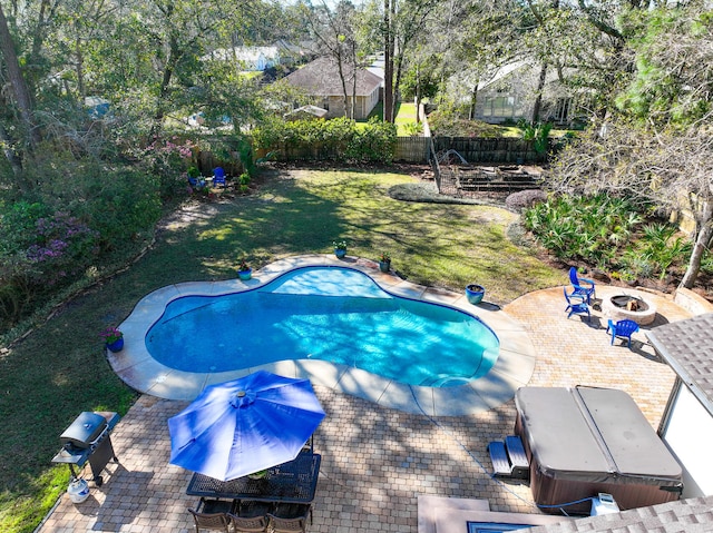 view of swimming pool featuring a patio, a yard, a fenced backyard, a hot tub, and a fire pit