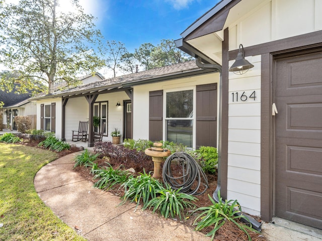 property entrance with a lawn and a shingled roof