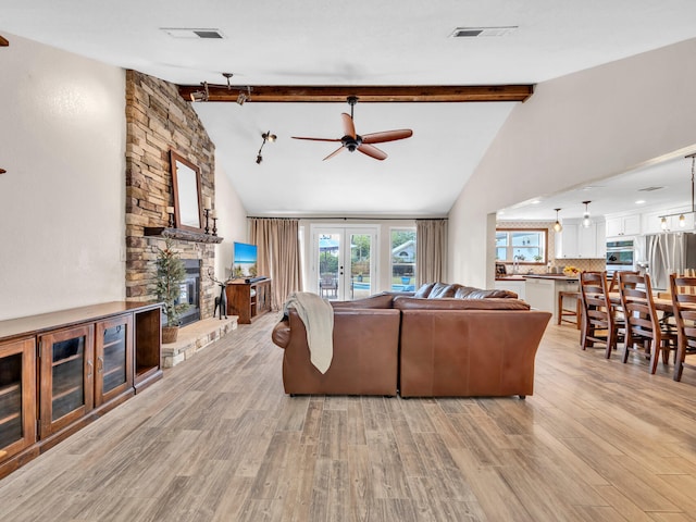 living area featuring visible vents, beam ceiling, ceiling fan, and light wood-style flooring