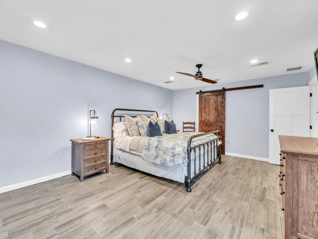 bedroom featuring recessed lighting, a barn door, baseboards, and light wood-style flooring