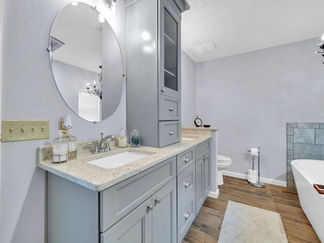 bathroom featuring a sink, a freestanding bath, wood finished floors, and double vanity