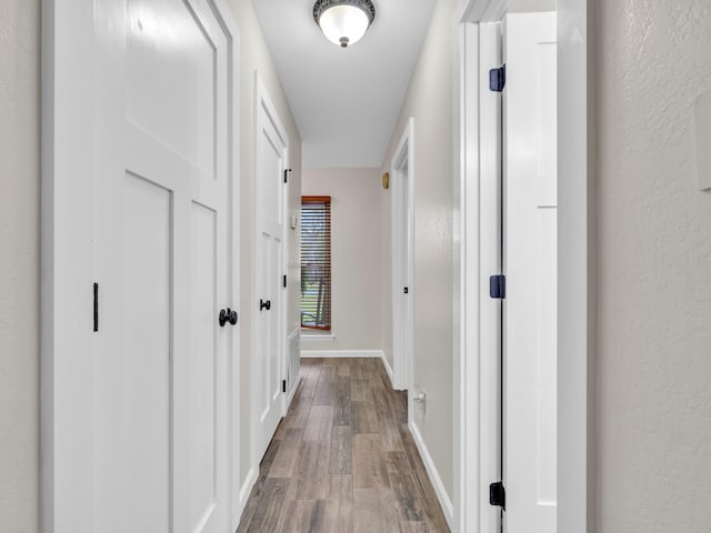 hallway featuring baseboards and dark wood-type flooring