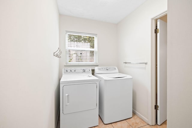 laundry area with light tile patterned floors, baseboards, washing machine and dryer, and laundry area