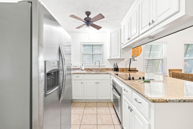 kitchen with appliances with stainless steel finishes, white cabinetry, a peninsula, and a sink