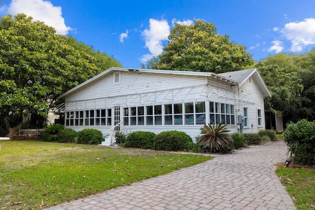 view of front facade with a front lawn and a sunroom