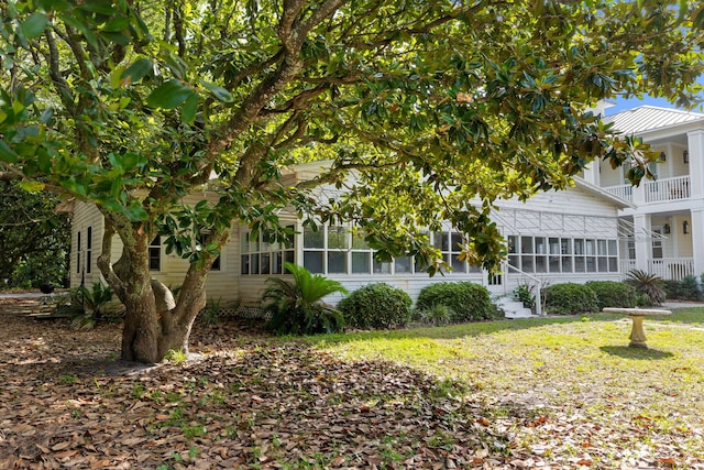 view of front facade featuring a balcony, a front yard, and a sunroom