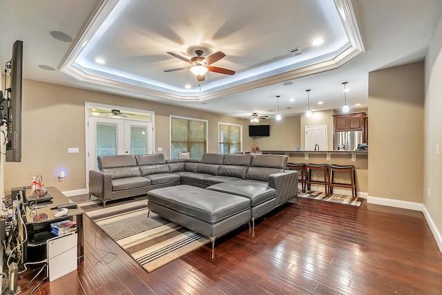 living area featuring visible vents, french doors, a tray ceiling, and hardwood / wood-style floors