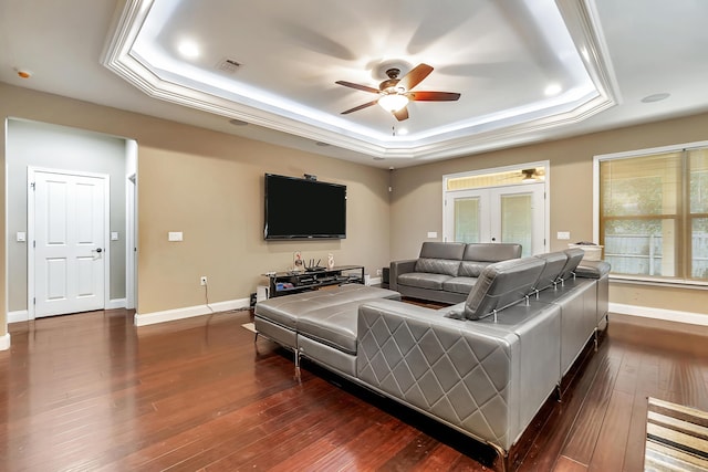 living room featuring visible vents, dark wood-type flooring, a ceiling fan, baseboards, and a raised ceiling