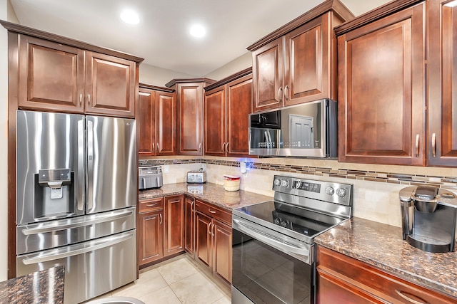 kitchen featuring dark stone countertops, tasteful backsplash, appliances with stainless steel finishes, and light tile patterned floors